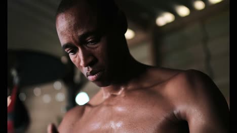 African-American-male-boxer-wearing-hand-wrap-in-fitness-studio-4k