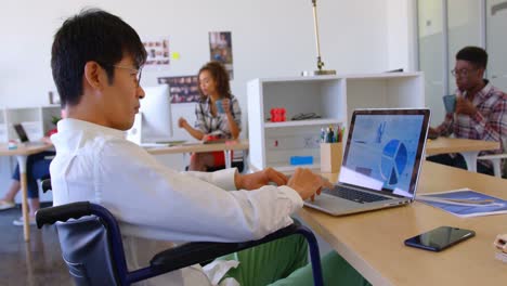 Behinderte-Asiatische-Männliche-Führungskraft-Mit-Laptop-Am-Schreibtisch-Im-Modernen-Büro-4k