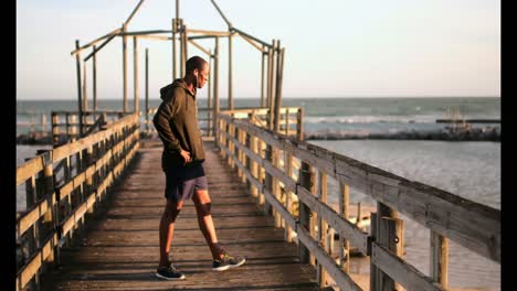 African-American-male-jogger-walking-on-pier-at-beach-in-the-sunshine-4k
