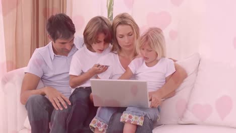Family-using-laptop-while-sitting-on-sofa