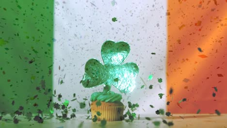 Paper-shamrocks-falling-down-and-cupcake-with-shamrock-decoration-against-irish-flag
