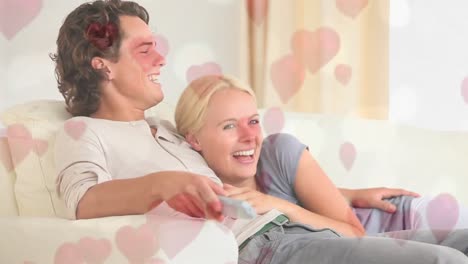 Couple-sitting-on-sofa-in-living-room-with-hearts-