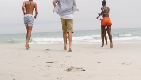 Rear-view-of-mixed-race-friends-running-towards-sea-at-beach-4k
