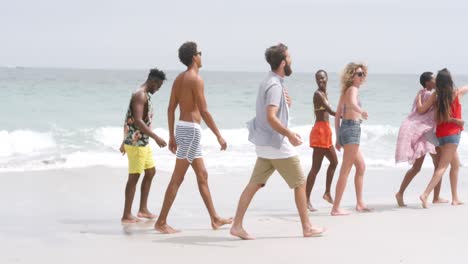 Side-view-of-mixed-race-friends-walking-on-the-beach-4k