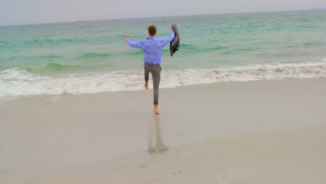 Rear-view-of-Caucasian-Businessman-running-with-blazer-on-the-beach-4k