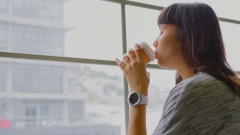 Businesswoman-drinking-coffee-while-sitting-near-window-in-a-modern-office-4k