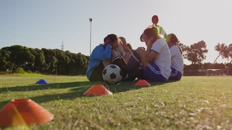 Female-soccer-players-doing-sit-up-exercises-while-captain-gives-training-on-soccer-field.-4k