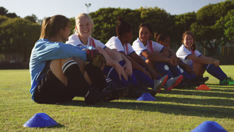 Female-soccer-team-sitting-on-the-ground-while-talking-on-soccer-field.-4k