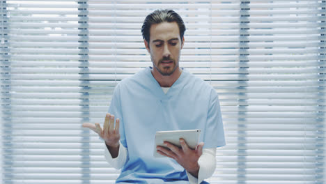 Young-male-doctor-using-tablet-and-talking-to-camera-4k