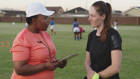 Young-adult-female-rugby-player-and-coach-at-training