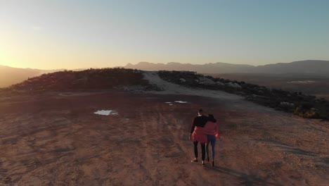 Young-couple-on-a-road-trip-walking-to-top-of-mountain-at-dusk
