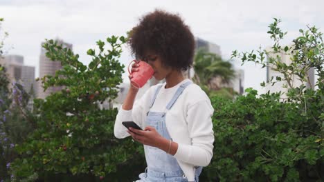 Mixed-race-woman-drinking-coffee-on-rooftop