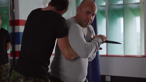 Caucasian-man-learning-self-defense-from-trainer-in-gym