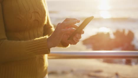 Senior-woman-using-smartphone-alongside-beach