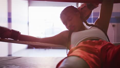 Mixed-race-woman-resting-in-boxing-gym