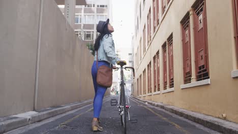 Mixed-race-woman-walking-next-to-her-bike-on-the-street
