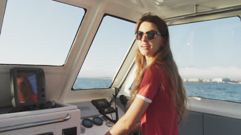 Side-view-of-a-teenage-Caucasian-girl-driving-a-boat-and-looking-at-camera