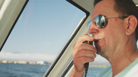 Rear-view-of-a-Caucasian-man-on-boat-using-a-walkie-talkie