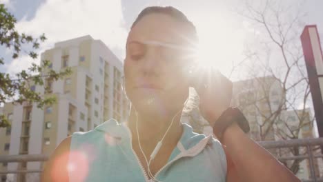 Sporty-Caucasian-woman-putting-her-headphones-on-outdoor