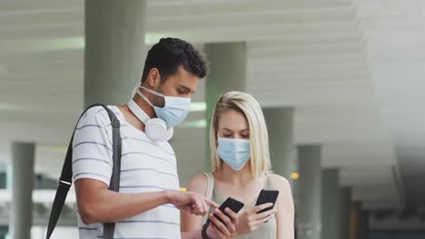 Caucasian-couple-on-the-go-wearing-a-coronavirus-covid19-mask-and-using-phone