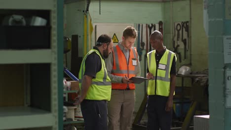 Two-Caucasian-and-an-African-American-male-factory-worker-in-discussion-