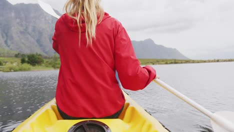 Caucasian-woman-having-a-good-time-on-a-trip-to-the-mountains,-kayaking-on-a-lake,-holding-a-paddle