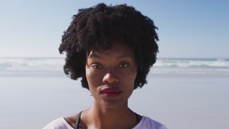 Afroamerikanische-Frau-Blickt-In-Die-Kamera-Und-Lächelt-Am-Strand-Und-Im-Hintergrund-Des-Blauen-Himmels