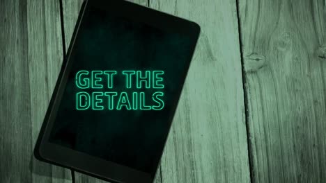 Animation-of-green-neon-style-words-Get-The-Details-flickering-on-screen-of-digital-tablet-