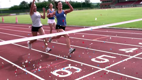 Digital-composite-video-of-multi-colored-confetti-falling-against-three-women-finishing-a-race