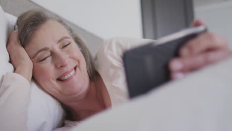 Woman-having-a-video-chat-on-her-smartphone-in-bed-at-home