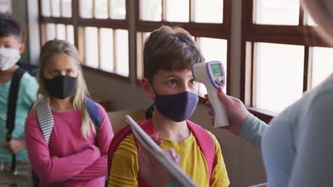 Junge-Mit-Gesichtsmaske-Lässt-Im-Unterricht-In-Der-Schule-Seine-Temperatur-Messen