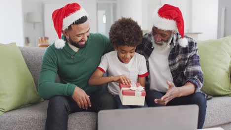 Father-son-and-grandfather-opening-gift-box-while-having-video-chat-on-laptop