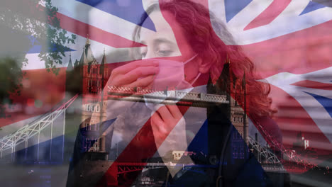 British-flag-waving-over-woman-wearing-a-face-mask-against-cityscape
