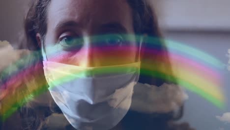 Rainbow-and-blue-sky-against-woman-wearing-face-mask
