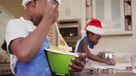 African-american-boy-and-girl-wearing-aprons-baking-together-in-the-kitchen-at-home