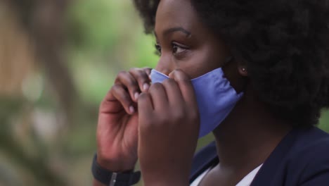 Afroamerikanische-Frau,-Die-Im-Park-Eine-Gesichtsmaske-Aufsetzt