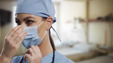Female-caucasian-surgeon-adjusting-her-face-mask-in-hospital