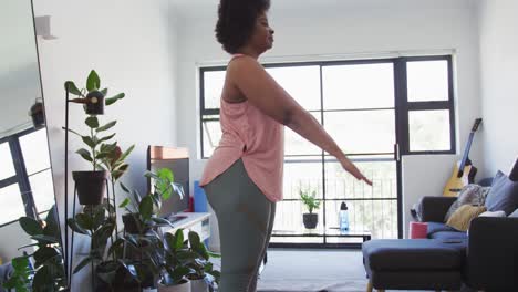 African-american-female-plus-size-standing-on-exercise-mat-doing-sit-ups