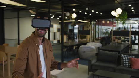 Mixed-race-businessman-standing-anfd-using-vr-googles-in-a-modern-office