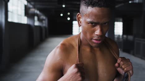 Shirtless-african-american-man-tired-after-skipping-the-rope-in-an-empty-urban-building