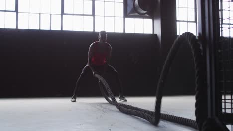 African-american-man-exercising-battling-ropes-in-an-empty-urban-building