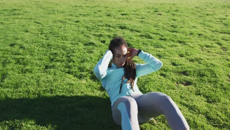 African-american-woman-in-sportswear-doing-sit-ups-in-park