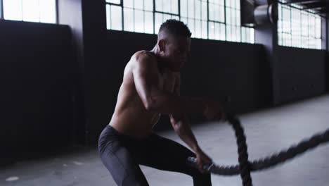 Shirtless-african-american-man-exercising-battling-ropes-in-an-empty-urban-building
