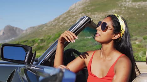 African-american-woman-wearing-sunglasses-sitting-in-the-convertible-car-on-road