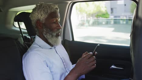 African-american-senior-man-using-smartphone-while-sitting-in-the-car