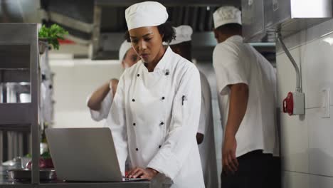 African-american-female-chef-using-laptop-in-restaurant-kitchen