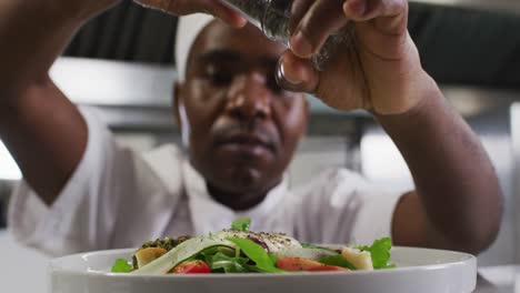 African-american-male-chef-garnishing-dish-in-restaurant-kitchen