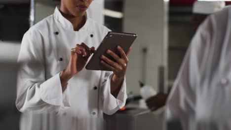 African-american-female-chef-using-tablet-in-restaurant-kitchen