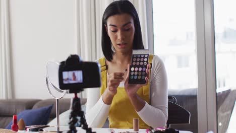 Mixed-race-gender-fluid-vlogger-recording-a-make-up-vlog-at-home