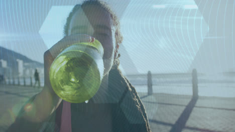 Hexagonal-shapes-against-african-american-woman-drinking-water-on-promenade